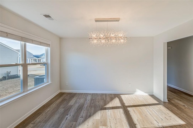 unfurnished dining area with an inviting chandelier and hardwood / wood-style flooring