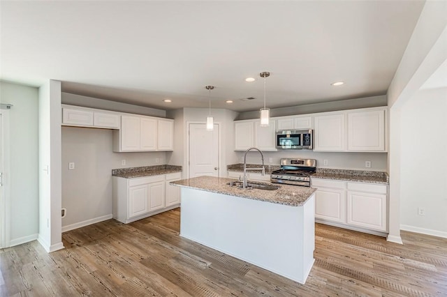 kitchen featuring a center island with sink, appliances with stainless steel finishes, hanging light fixtures, white cabinets, and sink