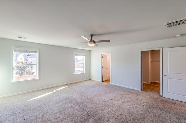 unfurnished bedroom featuring a spacious closet, multiple windows, a closet, and ceiling fan