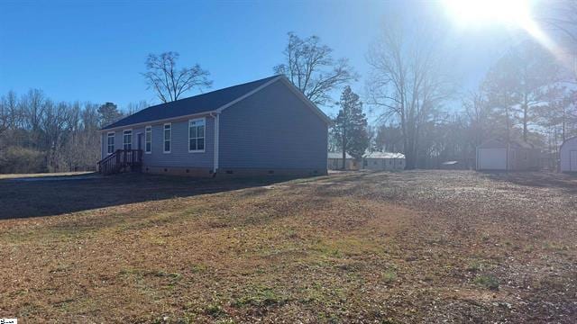 view of side of home with a yard and a shed