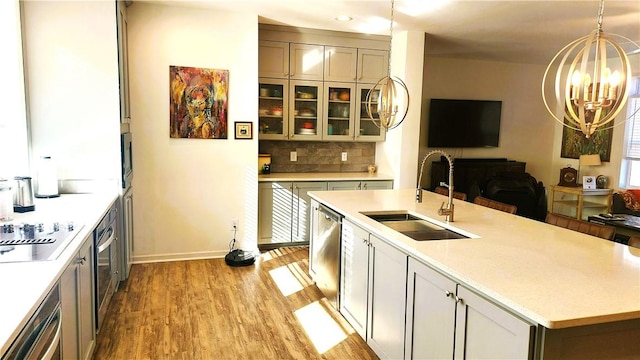 kitchen with decorative light fixtures, sink, a notable chandelier, light hardwood / wood-style floors, and stainless steel appliances