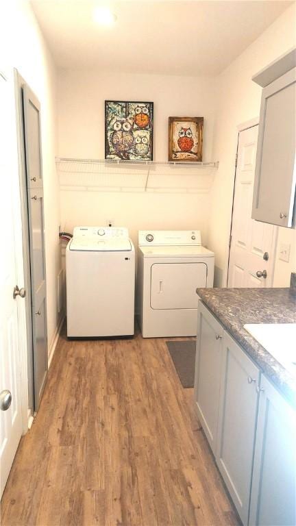 washroom featuring hardwood / wood-style flooring, cabinets, washer and clothes dryer, and sink