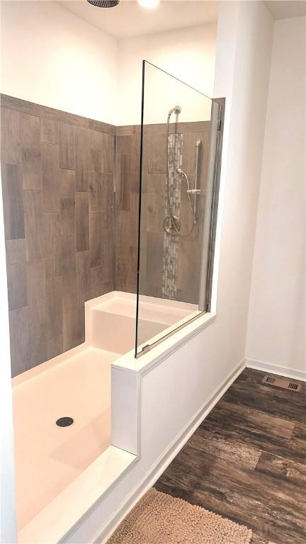 bathroom featuring hardwood / wood-style flooring and a tile shower