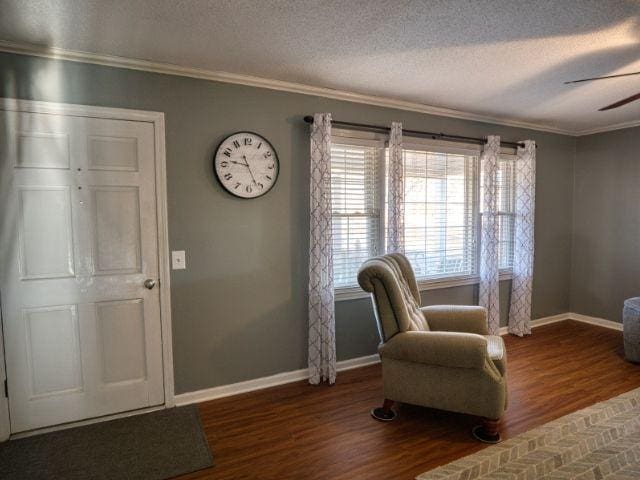 sitting room with ceiling fan, dark hardwood / wood-style flooring, ornamental molding, and a textured ceiling