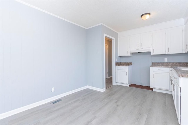 kitchen with white cabinets, a textured ceiling, ornamental molding, and light hardwood / wood-style floors