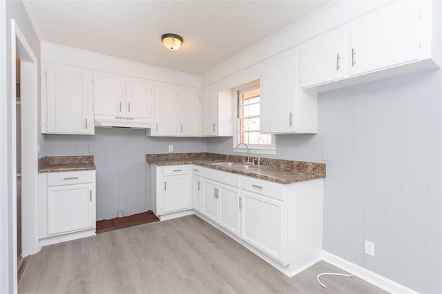 kitchen featuring a textured ceiling, light hardwood / wood-style flooring, white cabinets, and sink