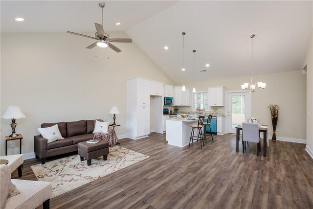 living room with high vaulted ceiling, dark hardwood / wood-style flooring, and ceiling fan with notable chandelier