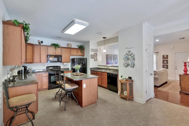 kitchen with decorative light fixtures, a kitchen island, black appliances, sink, and a kitchen breakfast bar