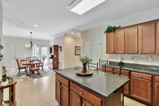 kitchen with a chandelier, pendant lighting, ornamental molding, and a center island