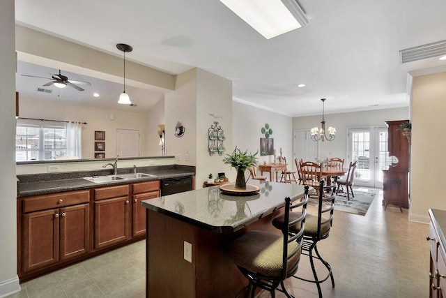 kitchen with a kitchen island, sink, black dishwasher, a breakfast bar area, and ceiling fan with notable chandelier