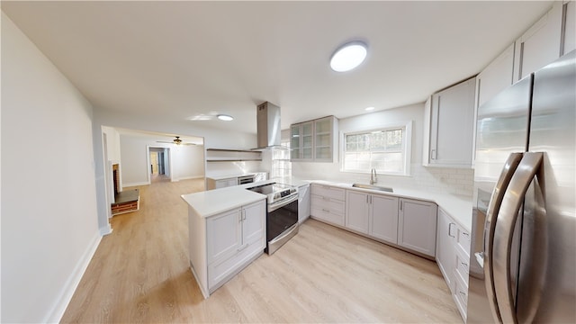 kitchen featuring island exhaust hood, stainless steel appliances, sink, backsplash, and light hardwood / wood-style flooring