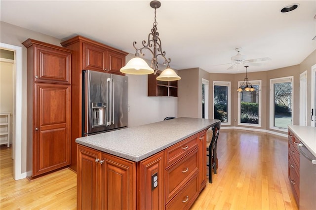 kitchen with hanging light fixtures, ceiling fan, appliances with stainless steel finishes, and light wood-type flooring