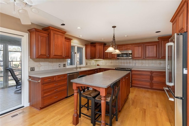 kitchen featuring light hardwood / wood-style floors, a center island, sink, a kitchen breakfast bar, and stainless steel appliances