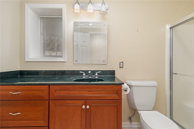 bathroom featuring toilet, an enclosed shower, and vanity