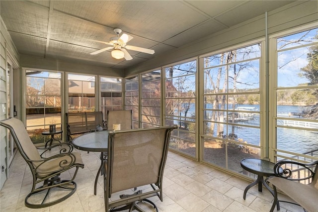 sunroom featuring ceiling fan and a water view