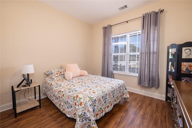 bedroom with dark wood-style floors, visible vents, and baseboards