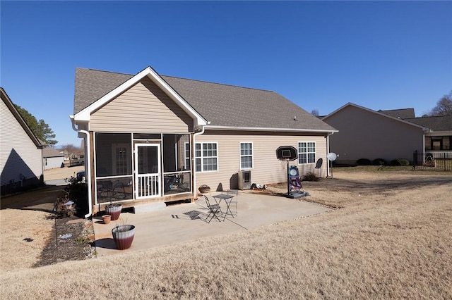 back of house with a shingled roof, a patio, and a sunroom