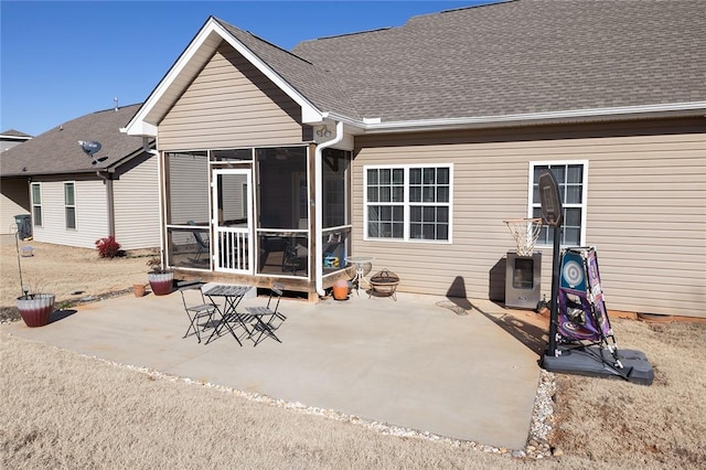 rear view of house with a patio area, a sunroom, and roof with shingles