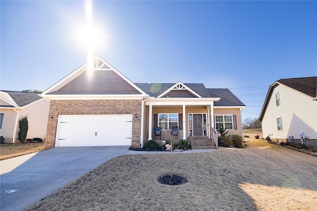 craftsman-style house featuring driveway, covered porch, a shingled roof, a garage, and brick siding