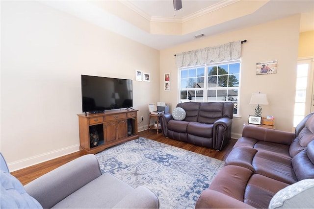 living room featuring a tray ceiling, wood finished floors, visible vents, and a healthy amount of sunlight