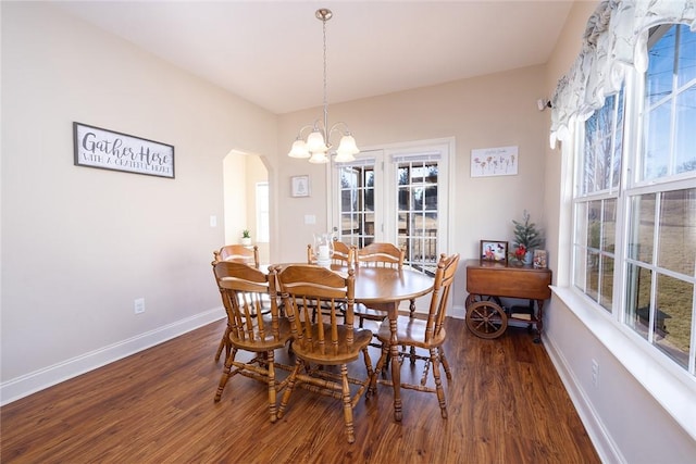 dining area featuring arched walkways, a notable chandelier, baseboards, and wood finished floors