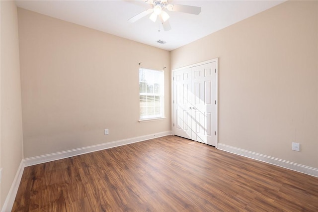 unfurnished bedroom with visible vents, baseboards, a closet, dark wood-style floors, and a ceiling fan