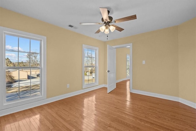 empty room with ceiling fan, a wealth of natural light, and light hardwood / wood-style floors