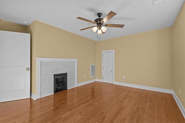 unfurnished living room with a brick fireplace, hardwood / wood-style floors, and ceiling fan