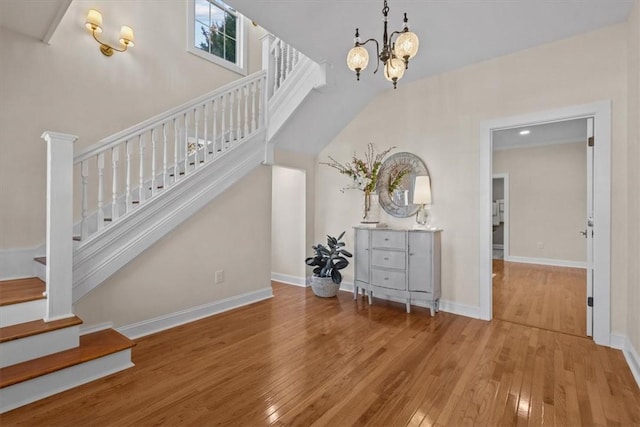 stairs with wood-type flooring and a notable chandelier