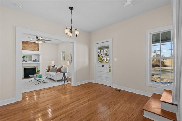 foyer with ceiling fan with notable chandelier and hardwood / wood-style floors