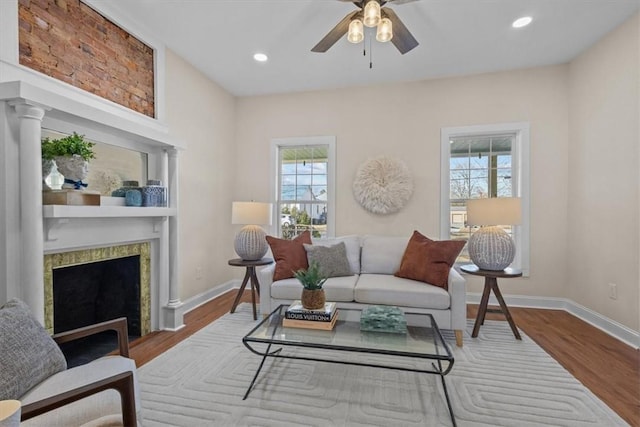 living room with ceiling fan, a high end fireplace, and wood-type flooring