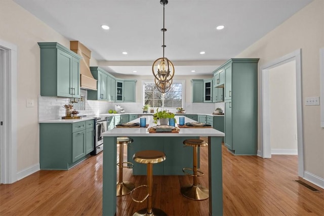 kitchen featuring light wood-type flooring, pendant lighting, tasteful backsplash, and electric range