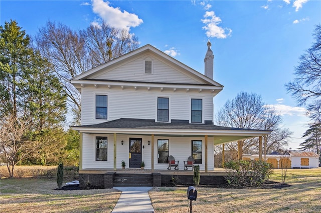 view of front of home with a porch, a chimney, and a front lawn