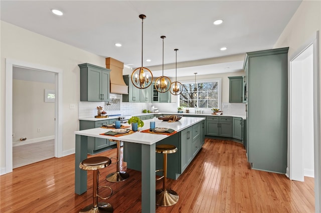 kitchen featuring light wood finished floors, a kitchen island, a breakfast bar, hanging light fixtures, and light countertops