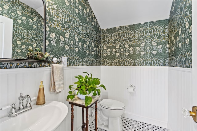 bathroom featuring wainscoting, a sink, and wallpapered walls