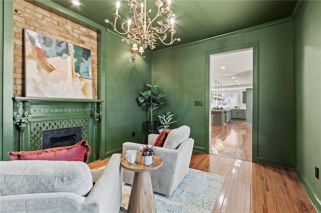 interior space featuring baseboards, hardwood / wood-style floors, an inviting chandelier, crown molding, and a fireplace