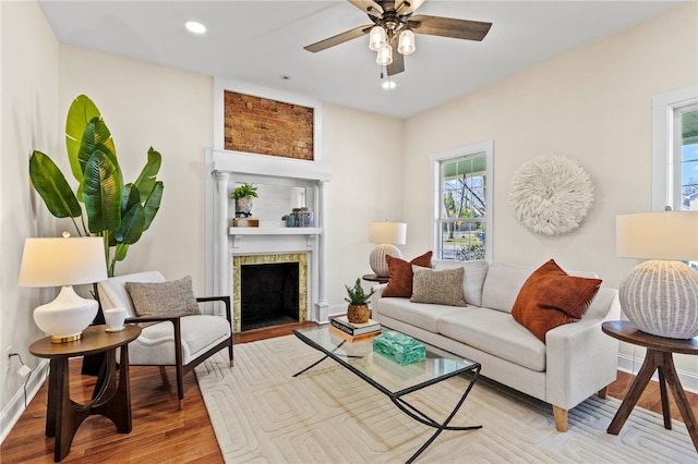 living area featuring ceiling fan, light wood-style flooring, recessed lighting, a fireplace with flush hearth, and baseboards