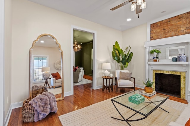 sitting room with baseboards, ceiling fan, wood finished floors, a fireplace, and recessed lighting