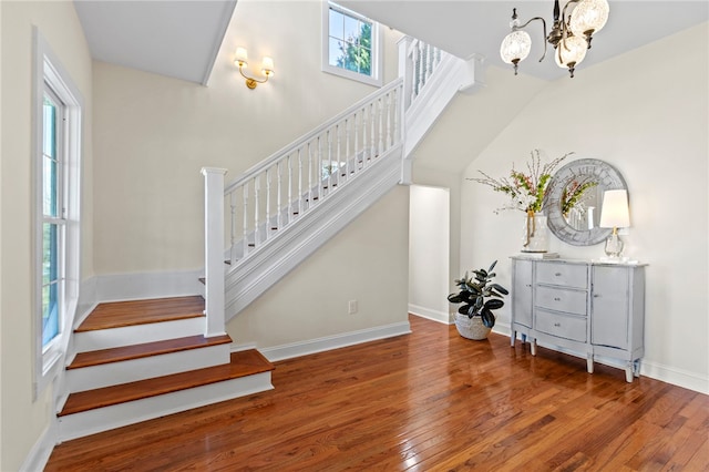 stairs featuring baseboards, a healthy amount of sunlight, hardwood / wood-style floors, and an inviting chandelier