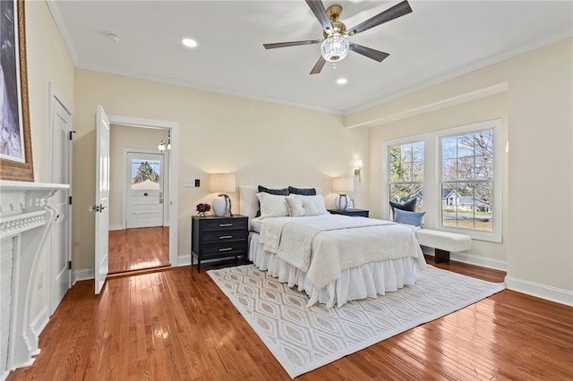 bedroom featuring baseboards, hardwood / wood-style floors, multiple windows, and crown molding