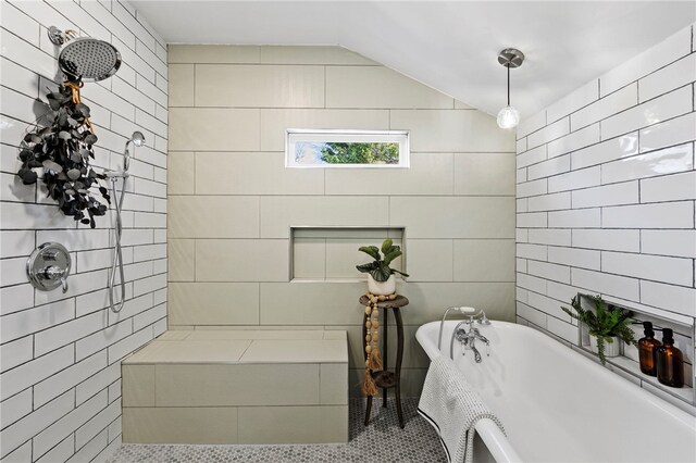 full bath featuring lofted ceiling, a freestanding tub, a tile shower, and tile walls