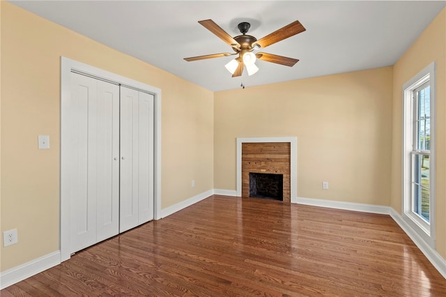 unfurnished living room featuring a fireplace, baseboards, and wood finished floors