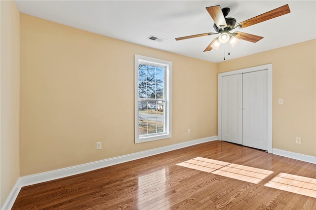 unfurnished bedroom featuring visible vents, a closet, baseboards, and wood finished floors