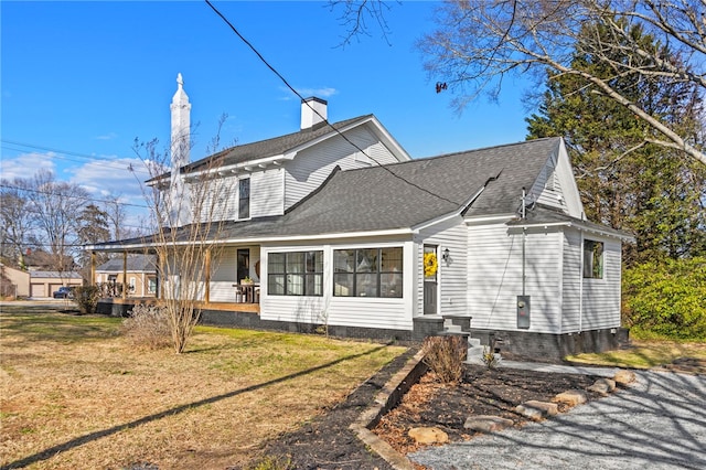 exterior space with a chimney, a lawn, and roof with shingles