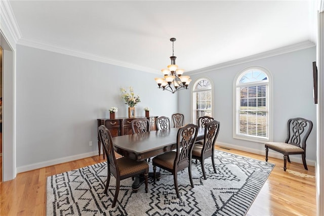 dining space featuring crown molding, an inviting chandelier, and light hardwood / wood-style flooring