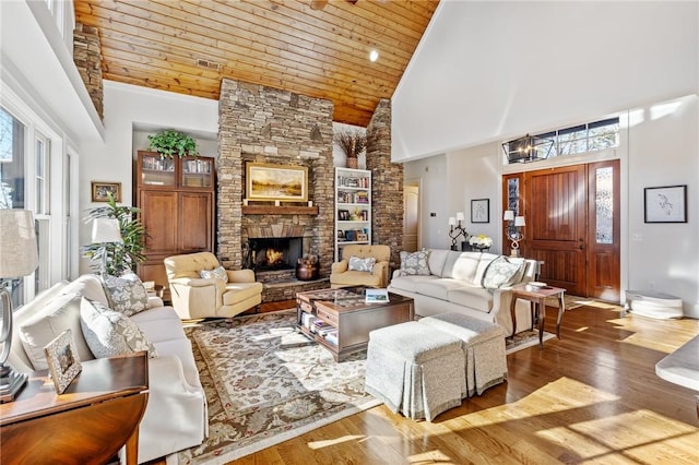 living room featuring high vaulted ceiling, dark hardwood / wood-style flooring, a stone fireplace, and wooden ceiling