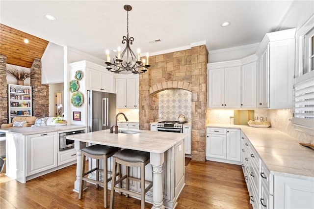 kitchen with a center island with sink, appliances with stainless steel finishes, decorative backsplash, white cabinets, and sink