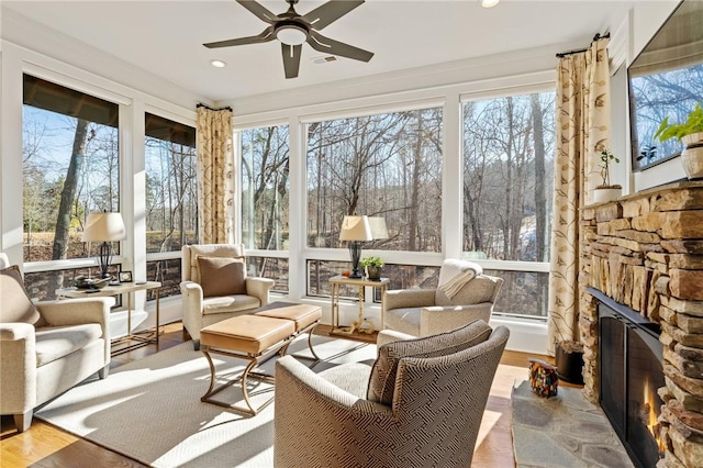 sunroom featuring ceiling fan, a healthy amount of sunlight, and a fireplace