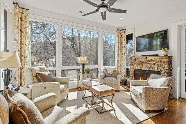 sunroom / solarium with ceiling fan, a healthy amount of sunlight, and a fireplace