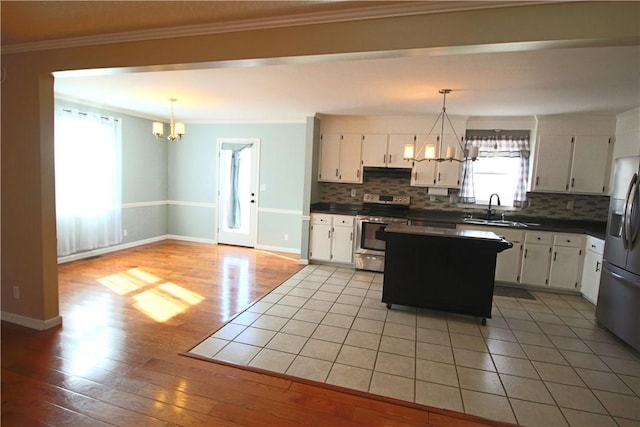 kitchen with hanging light fixtures, white cabinets, sink, and stainless steel appliances